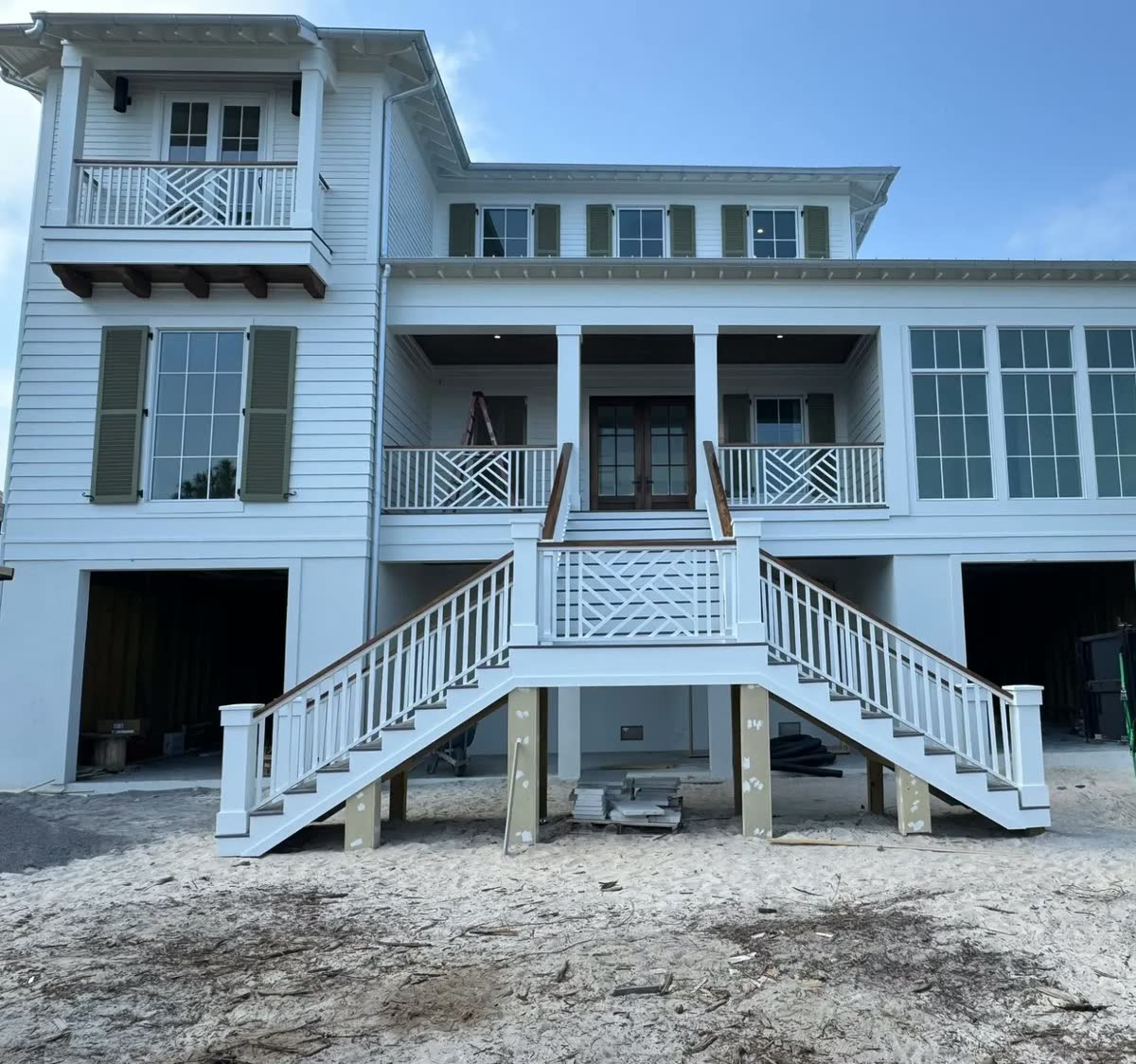 A white raised house with green shutters and a double front stair with chippendale railings.