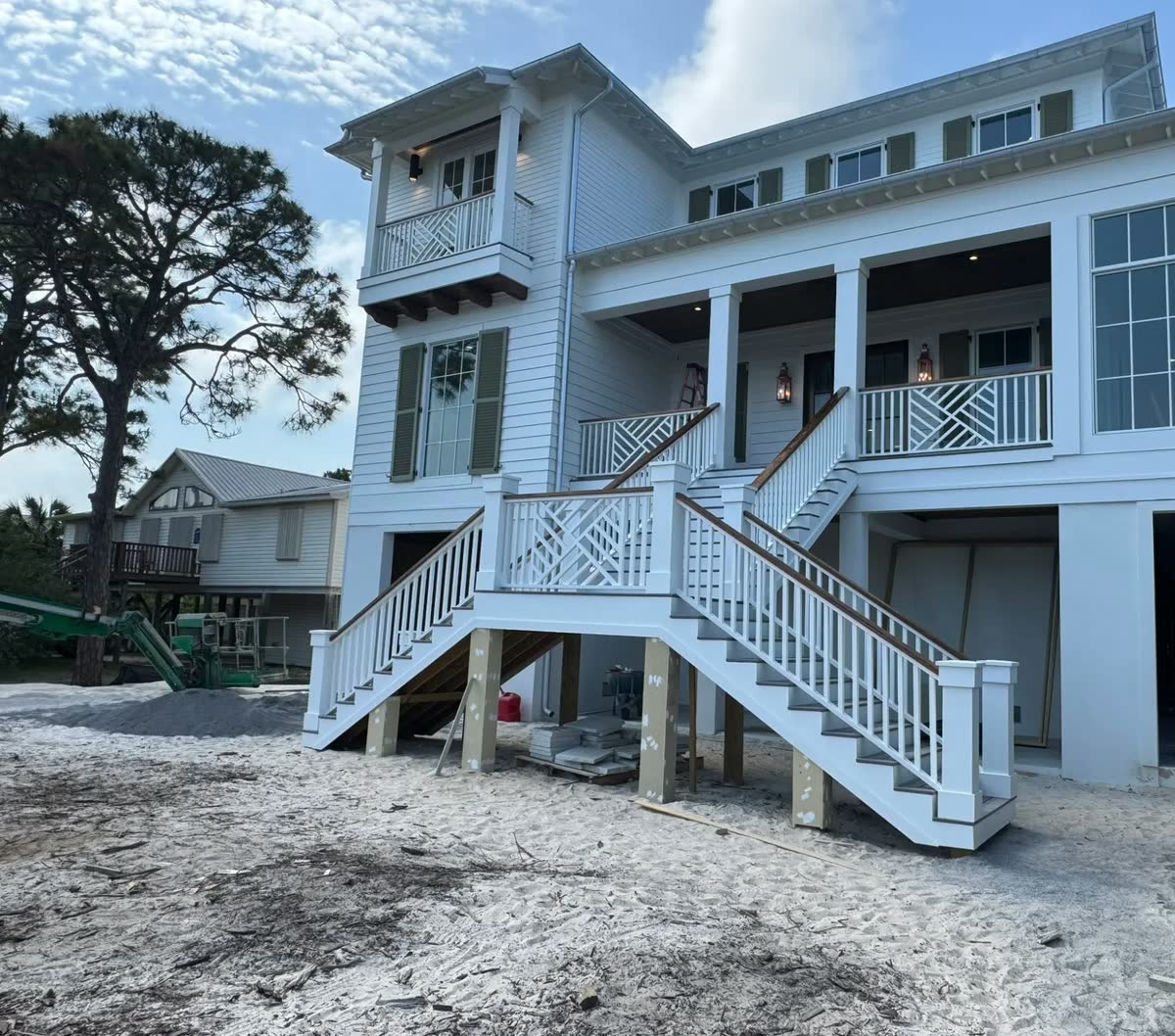 A wide double stair with white railings and wood handrails rising to a raised front porch.