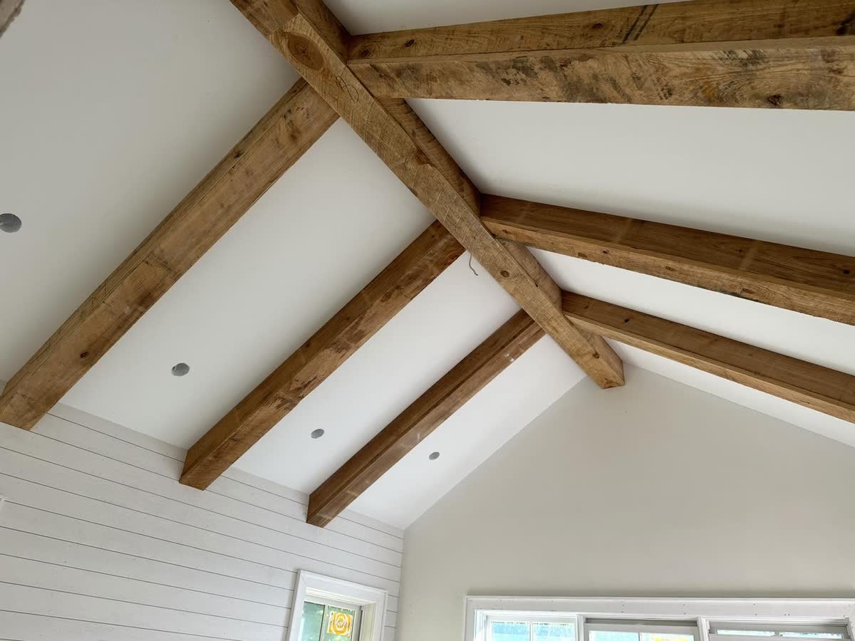Wood beams on a vaulted ceiling with white shiplap walls.