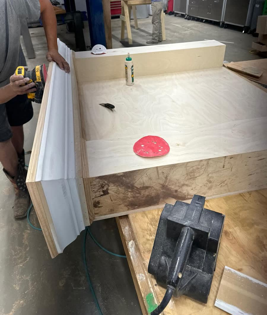 A cabinet being built on site, tools and parts on the floor.
