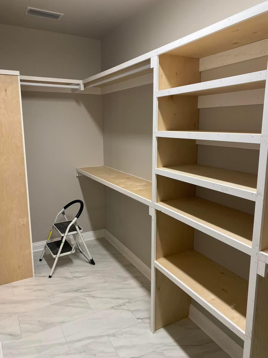 A walk-in closet with built-in shelving and hanging rods.