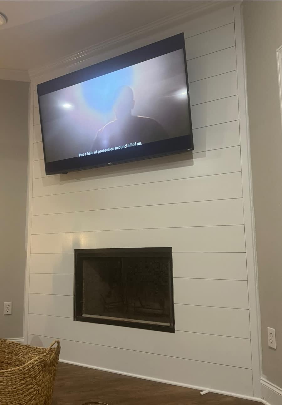 A shiplap feature wall with a fireplace below a mounted television.