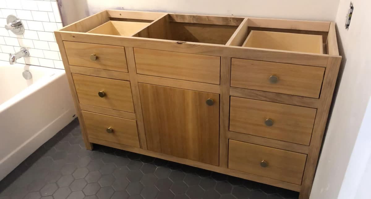 A new wood bathroom vanity with drawers and a cabinet, before the top goes on.