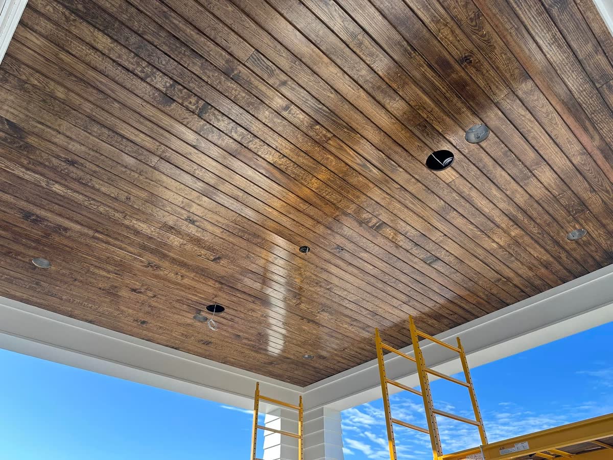 A tongue-and-groove wood ceiling stained a warm brown over a porch.