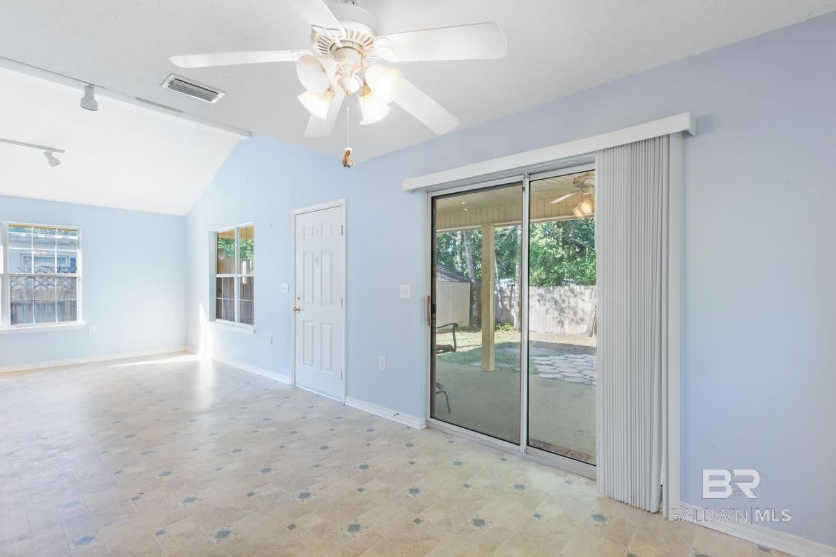 A bright living room with a ceiling fan and sliding glass doors to the back yard.