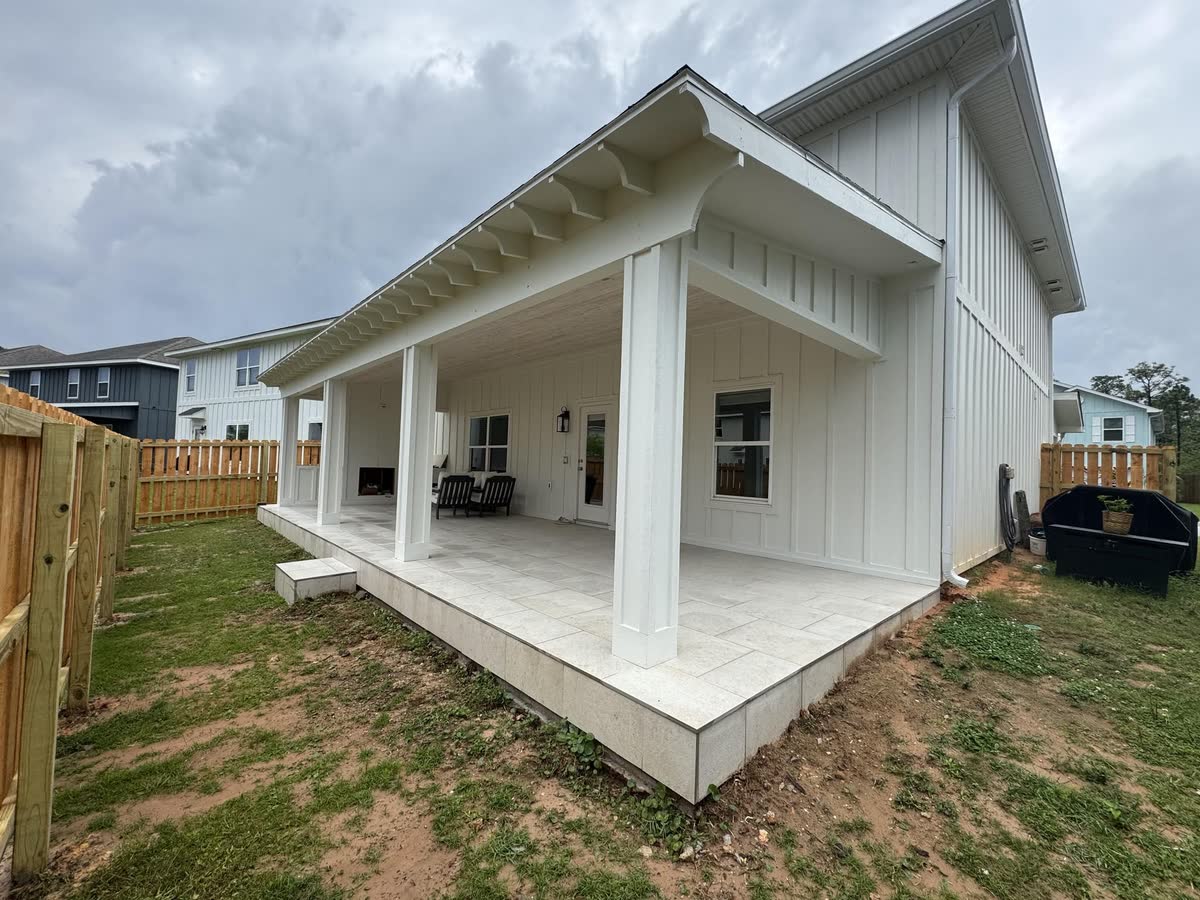 A new white board-and-batten house with a deep covered porch on square white columns.