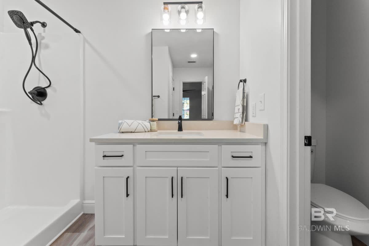 A bathroom vanity with white cabinets, a white top and a black faucet.