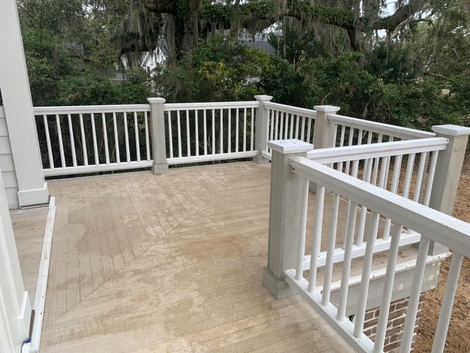 A deck with white railings and posts looking out to trees.