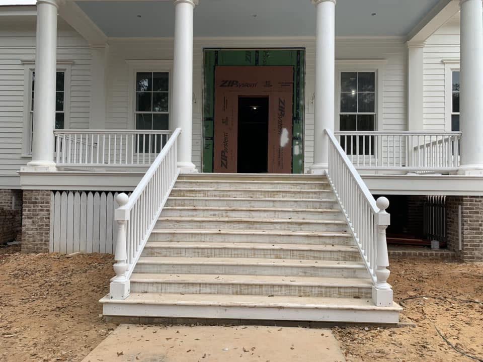 Wide front steps with white railings up to a porch with tall white columns.