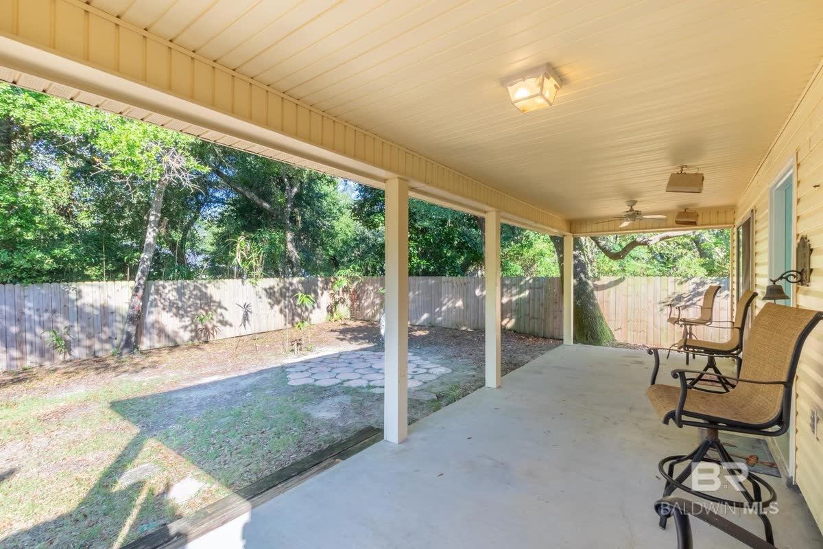A covered back patio with a wood-planked ceiling looking out to a fenced yard.