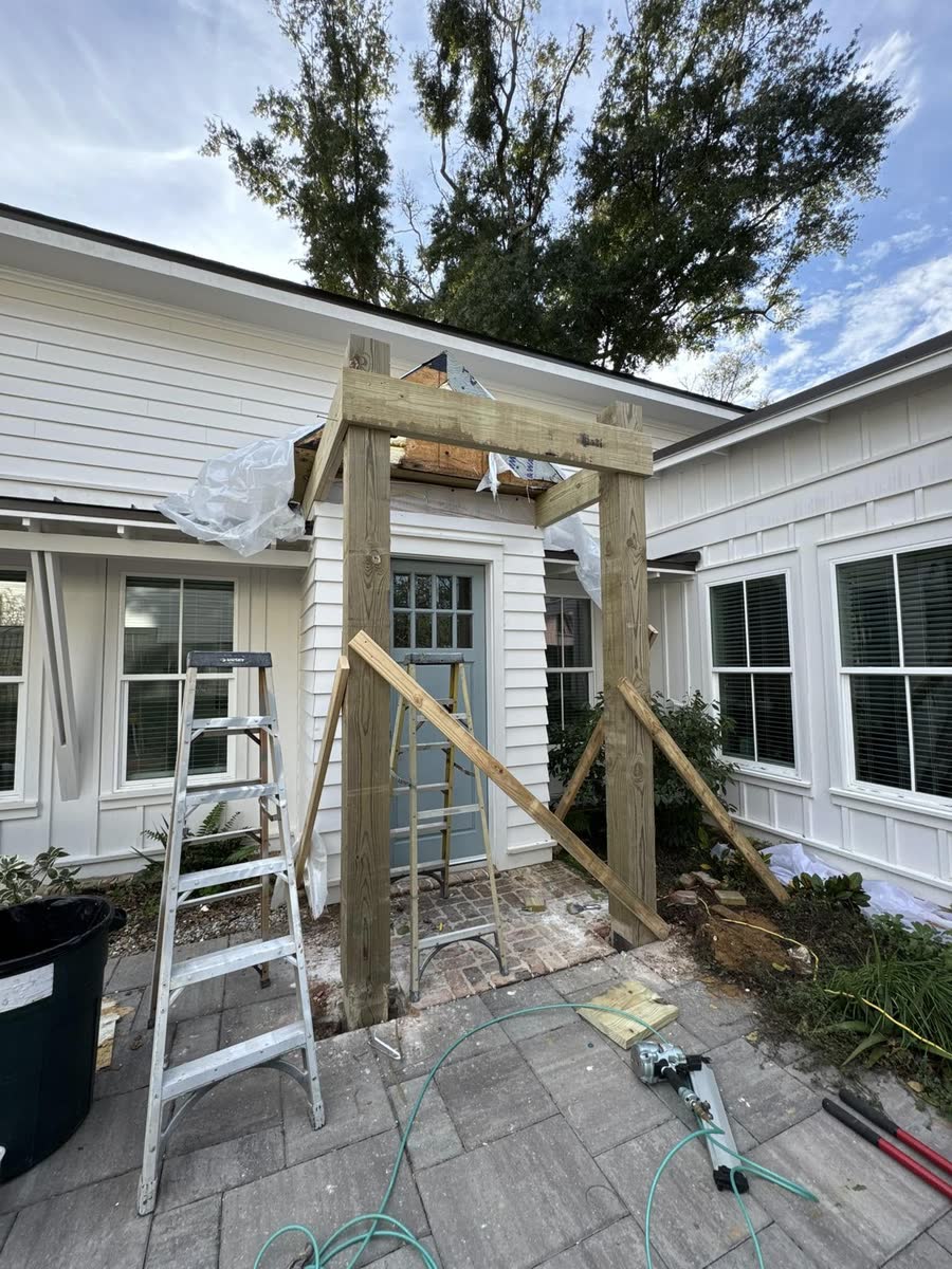 A portico being framed over a doorway, a ladder beside it.