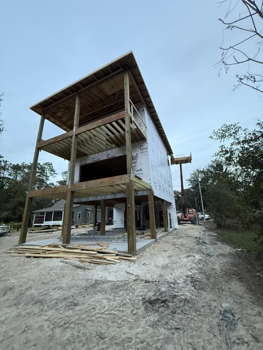 Two stacked porches framed on a raised house, the walls already wrapped.