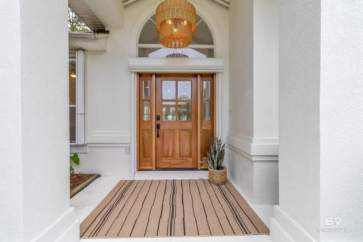 A wood front door with glass panes and a woven pendant light in the entry.