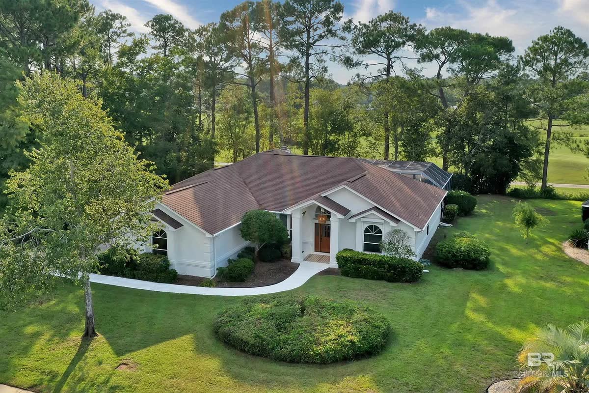 A remodeled home with a brown roof and white trim, a wood front door under an arch.