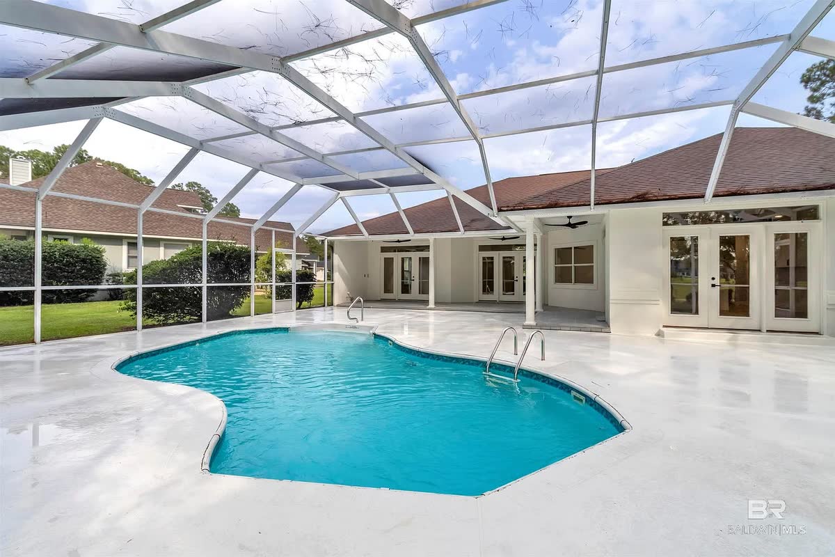 A screened pool enclosure with a kidney-shaped pool and a white deck.